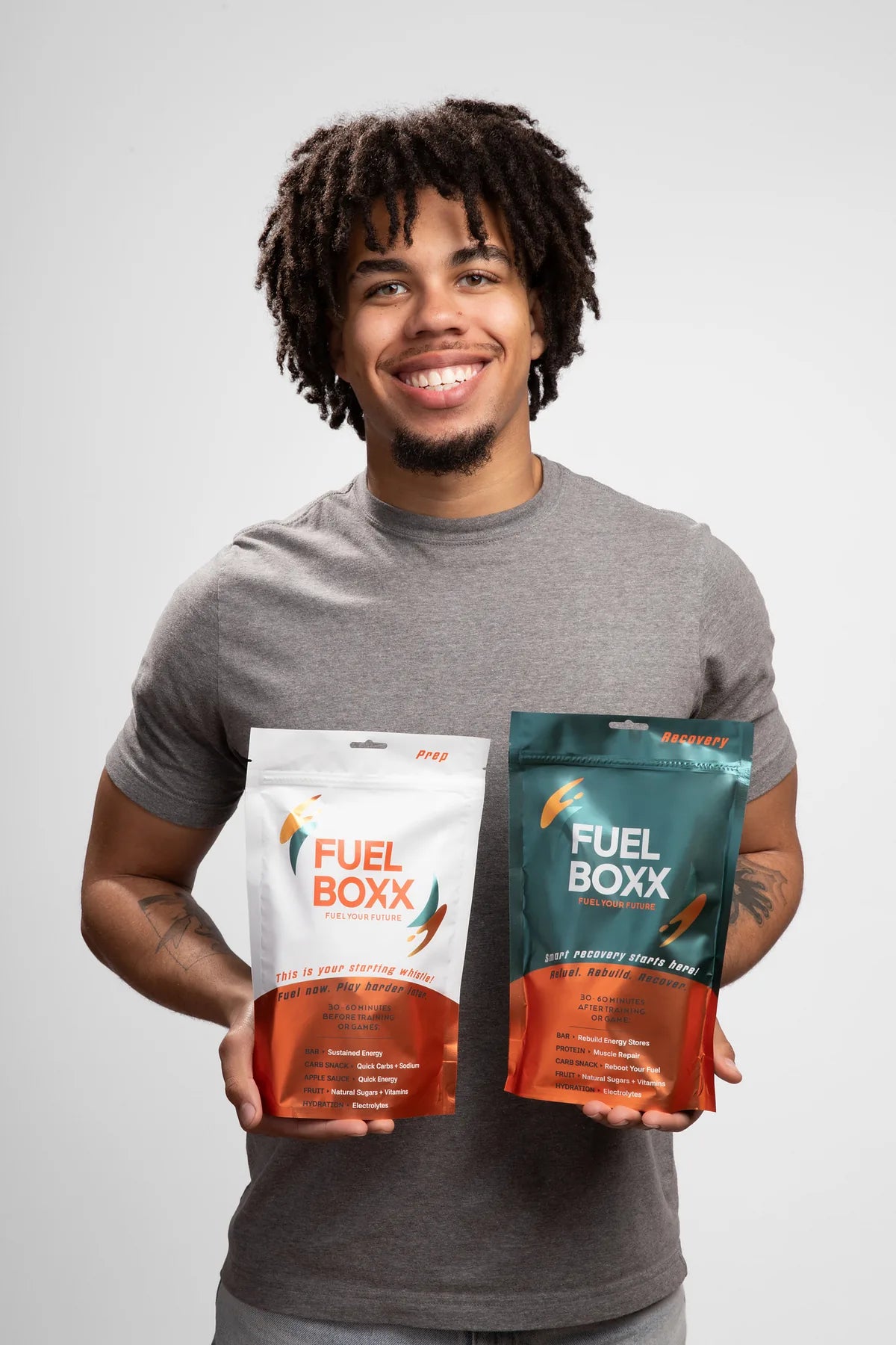 Smiling young athlete holding a Prep Pouch and a Recovery Pouch